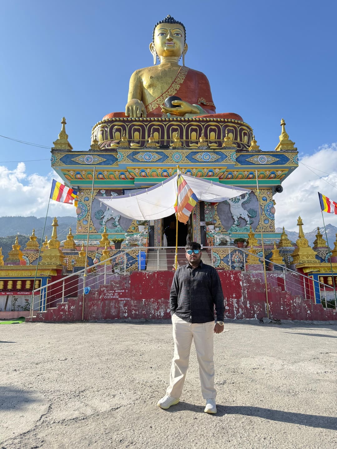 Omkar standing before the giant golden Buddha at Tawang