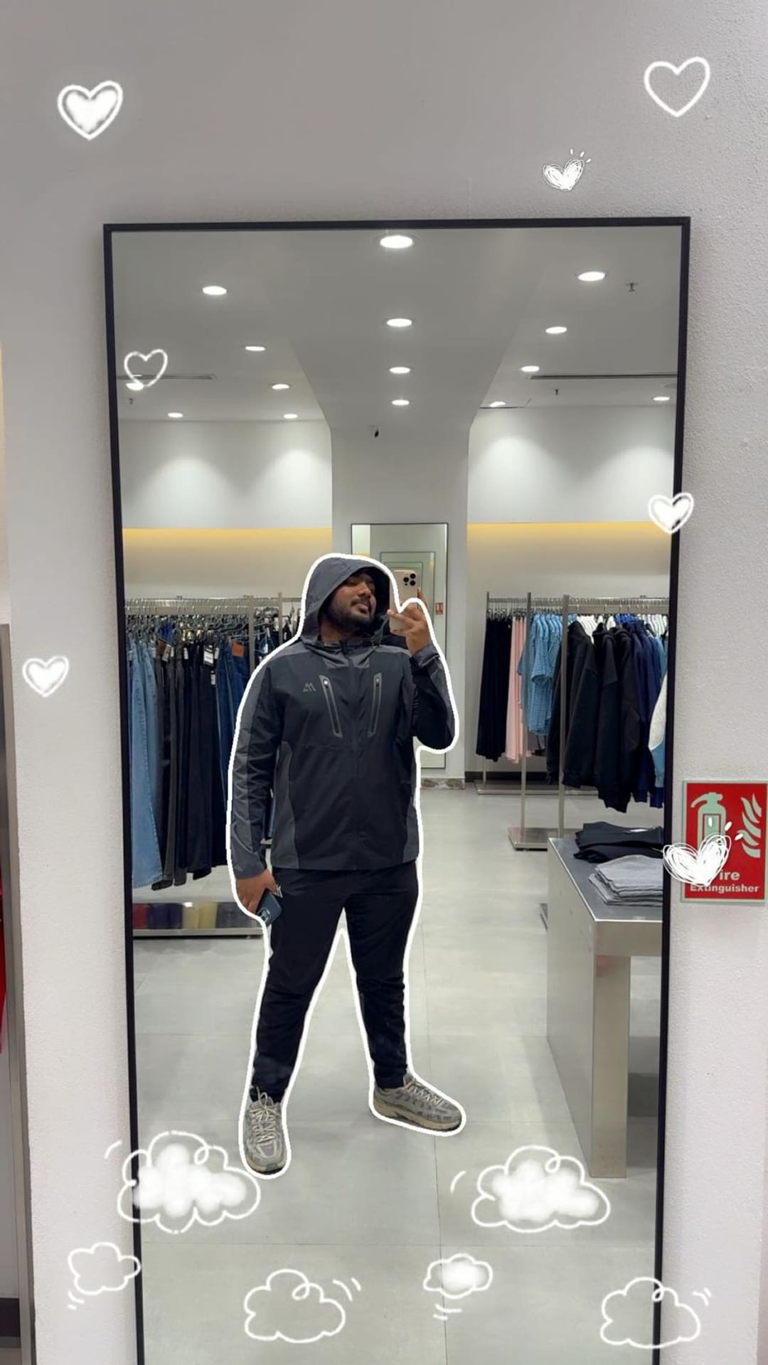Omkar taking a mirror photo in a fitting room, hood up